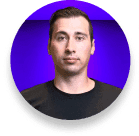 Man with short dark hair in a black T-shirt against a purple background