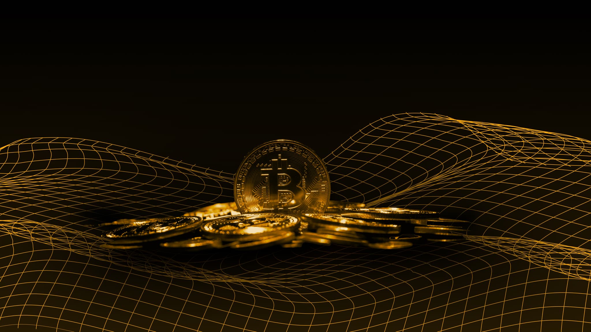 Gold Bitcoin coins resting on a glowing wireframe landscape